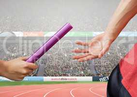 Athlete passing baton during relay race against stadium in background