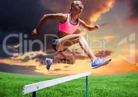 Athlete woman jumping over hurdle against cloudy sunset