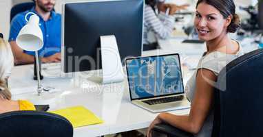 Portrait of smiling woman working on laptop at desk
