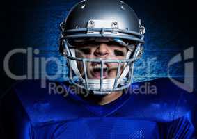 Aggressive american football player in helmet screaming against blue wall background