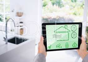 Hand holding digital tablet with home security icons on screen