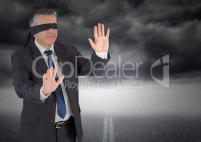 Businessman in blindfold against storm cloud
