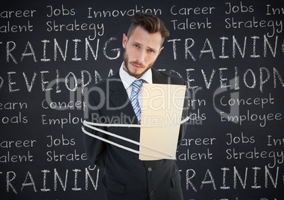 Portrait of businessman tied up with rope and folder against business concept on chalkboard