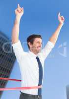Businessman celebrating at finish line against city building in background
