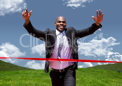 Businessman celebrating at finish line against green landscape