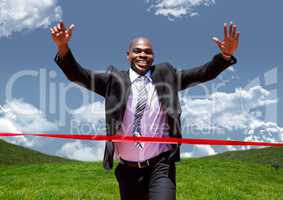 Businessman celebrating at finish line against green landscape