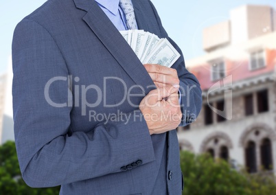 Mid section of businessman hiding money in blazer against house