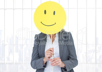 Businesswoman holding happy smiley face in front of her face against white background