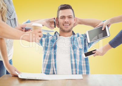 Relaxed businessman with hands holding electronic devices against yellow background