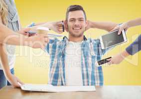Relaxed businessman with hands holding electronic devices against yellow background