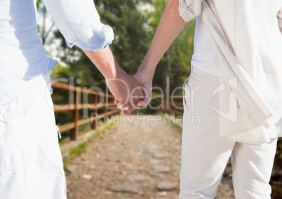 Mid section of couple holding hands walking on footbridge