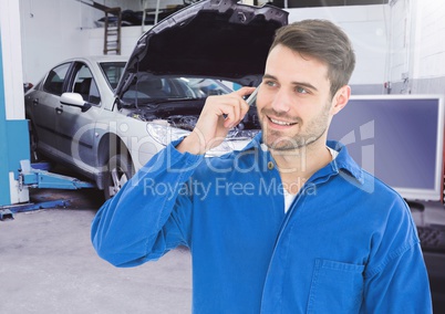 Automobile mechanic using mobile phone in workshop