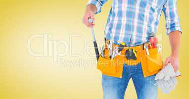Handy man standing with tools against yellow background