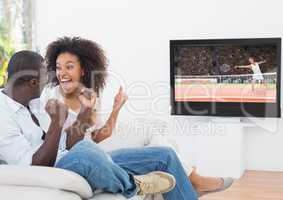 Couple cheering while watching tennis match on television