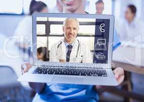 Woman holding a laptop with doctor on video call screen