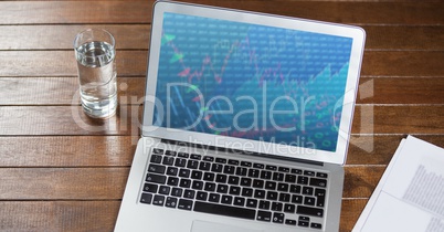 Laptop with document and glass of water on wooden table