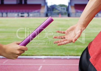 Mid-section of athlete passing the baton to teammate