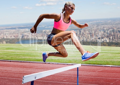 Athlete running over hurdle in stadium