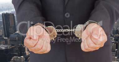 Businessman wearing handcuffs against cityscape