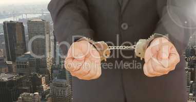 Businessman hands in handcuffs against city background