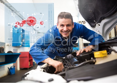 Mechanic working in garage against car mechanics interface in background
