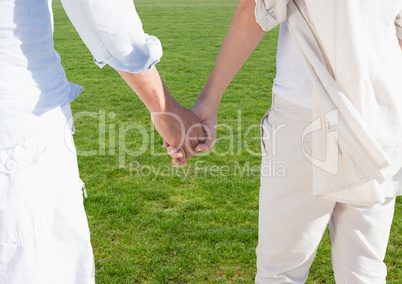 Couple holding hands walking on lawn