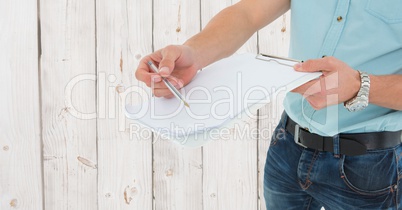 Delivery man holding a clipboard and pen against wooden background