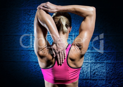 Fit woman doing stretching exercise against blue wall background