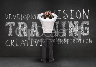 Thoughtful businessman standing against wall with business words