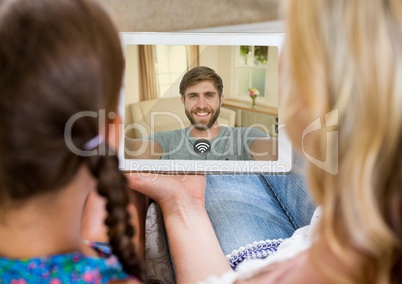 Mother and daughter having a video call with father in digital tablet