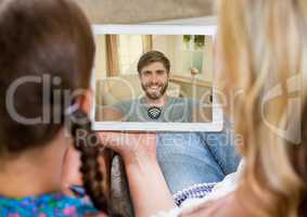 Mother and daughter having a video call with father in digital tablet
