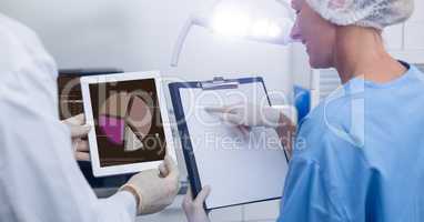 Smiling doctors discussing over digital tablet and clipboard