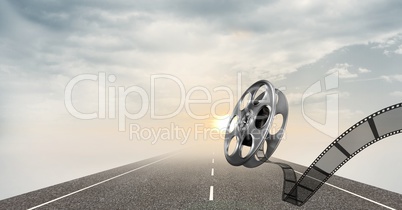 Film reel against road and sky in background