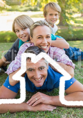 Happy family lying in park overlaid with house shape