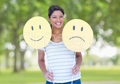 Happy woman holding smiley and sad face