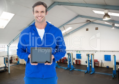 Mechanic holding a digital tablet against workshop in background