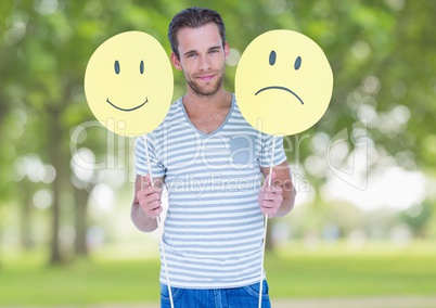 Conceptual image of man holding happy and sad smiley faces