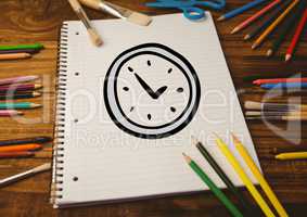 Hand drawn alarm clock on spiral note book and multi colored crayon wooden table