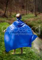 Rear view of kid in blue cape standing in field