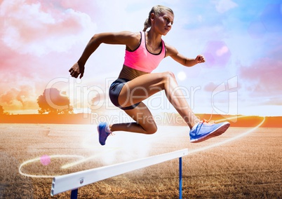Athlete running over hurdle in field against bright sunlight