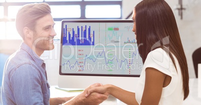 Colleagues shaking hands at office desk