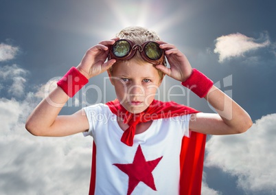 Confident boy wearing superhero costume standing against cloudy sky background