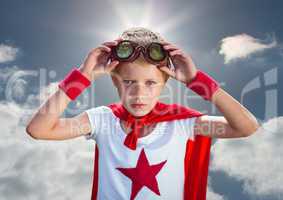 Confident boy wearing superhero costume standing against cloudy sky background