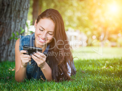 Mixed Race Young Female Texting on Cell Phone Outside In The Gra