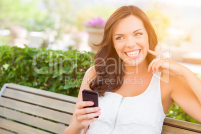 Smiling Young Adult Female Texting on Cell Phone Outdoors