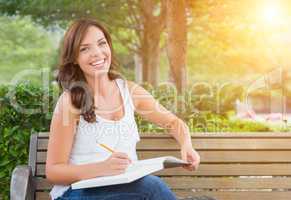 Young Adult Female Student with Pencil on Bench Outdoors