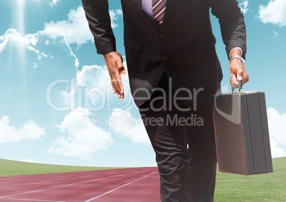 Businessman with briefcase on race track against sky in background