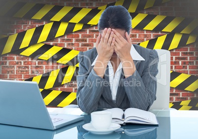 Tensed businesswoman sitting with hand on forehead against brick wall