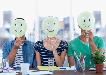 Executives sitting at desk with smiley faces on their face