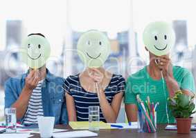 Executives sitting at desk with smiley faces on their face